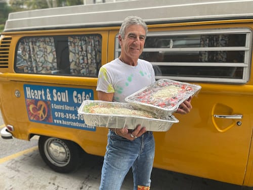 bud siciliano holding catering trays in front of yellow heart and soul van