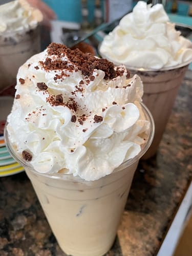 iced latte topped with whipped cream and brownie crumble