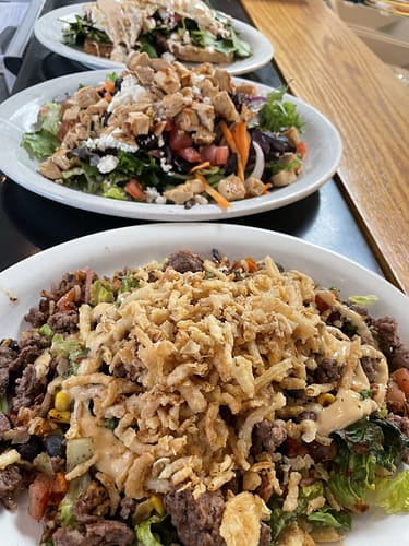 row of fresh salads with grilled chicken and steak