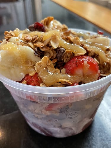 acai bowl topped with granola strawberries bananas and honey glaze