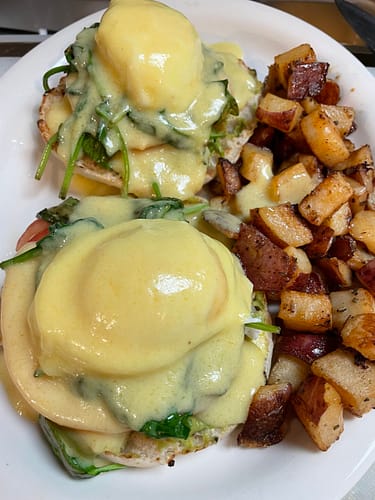 eggs benedict with spinach and tomato with homefries